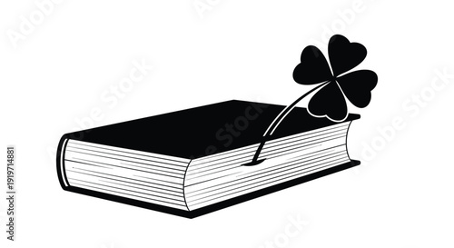 A four-leaf clover serves as a bookmark in a closed book.