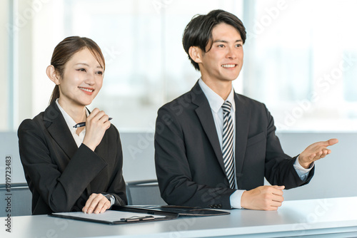 Quadro su tela Businessmen and businesswomen in suits standing at a desk (interviewer, company