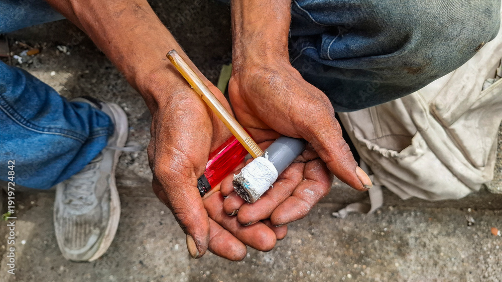 Φωτογραφία A stark detail of dirty hands holding a makeshift drug den in the street, a symbol of social exclusion, poverty, and health risks