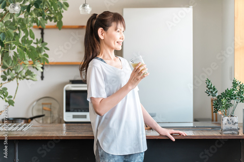 Bild auf Leinwand Middle-aged Asian woman rehydrating and replenishing nutrients after training in