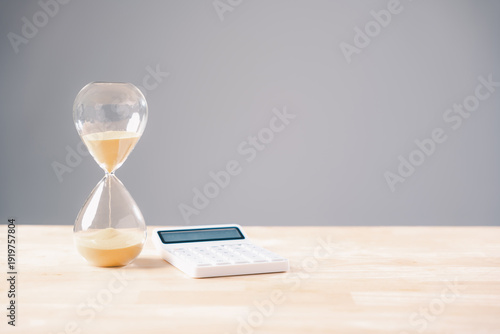 Bild auf Leinwand Hourglass sand flows showing tax time running short, calculator awaits business
