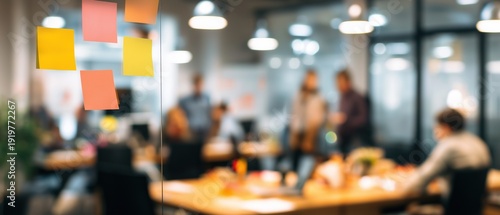 Creative office workspace with sticky notes on glass partition and blurred colleagues working in background, modern coworking environment for design thinking and project management