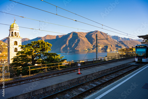 Commuter train and church tower above Lake Lugano in Switzerland