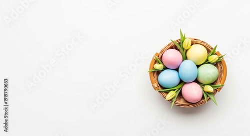 A basket of colorful Easter eggs with green leaves on a white background.