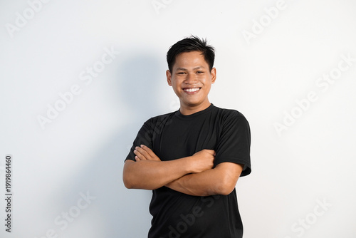 Smiling young Asian  man in a black shirt poses with arms crossed, conveying confidence, approachability, and casual style ideal for business, lifestyle, profile, and marketing uses.