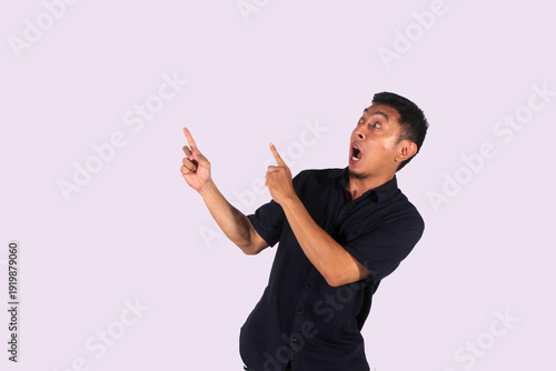 An Asian adult man wearing a black shirt smiles happily after getting a new idea, posing as he shows his idea to an empty space.