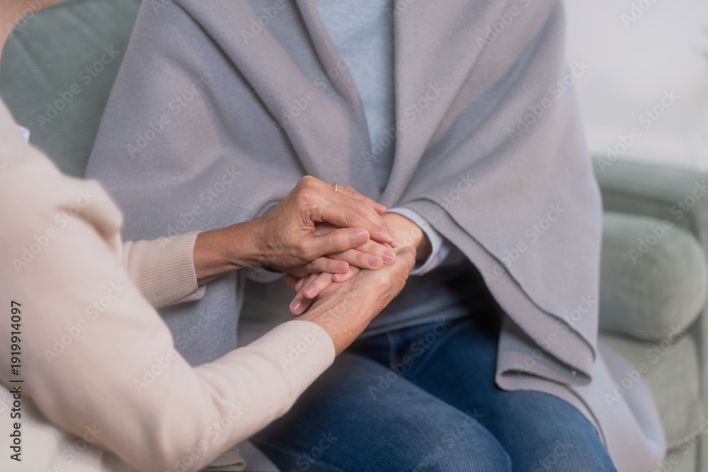 Obraz premium An elderly mother gently places a warm blanket around her shivering daughter on the sofa, expressing protective love, care, and comfort inside a calm, nurturing home environment