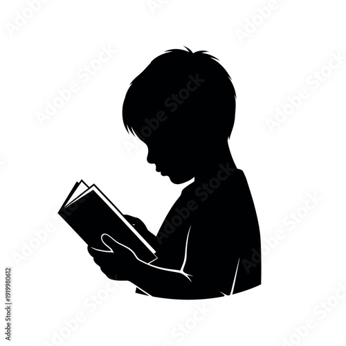 Silhouette of a young boy engrossed in reading a book side profile.