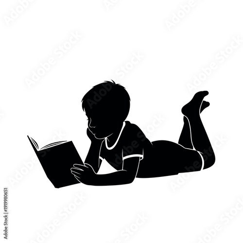 Silhouette of a young boy reading a book while lying down.