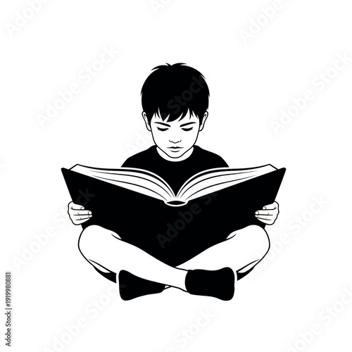 Young boy engrossed in reading a large book.