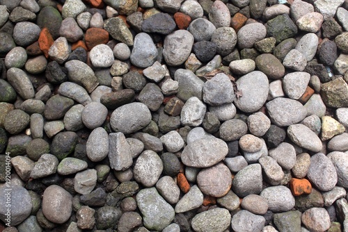 Close-up natural pebble stone texture background. Top view, showcasing a variety of smooth, rounded rocks in earthy tones
