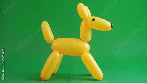 A bright yellow balloon dog stands against a vibrant green screen background, perfect for creative projects.
