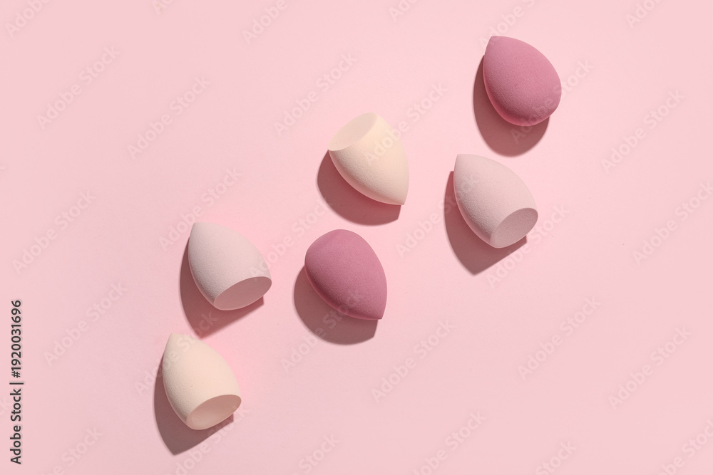 Fototapeta premium Many makeup sponges on pink background