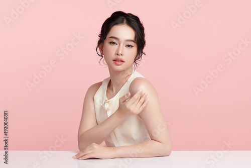 A beautiful young Asian woman with clean, fresh skin against a pink background. Skincare, facial treatment, cosmetology, beauty, and spa. An elegant portrait of an Asian woman.