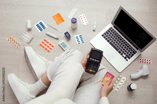 Woman with payment terminal, credit card, modern laptop, different medicines ...