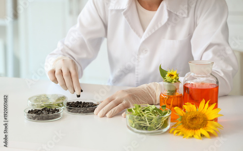 Happy female scientist with flasks of samples, sunflower seeds and sprouts wo...