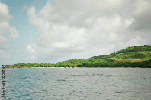 Green hills and snorkelers in calm water at Tamarindo Beach