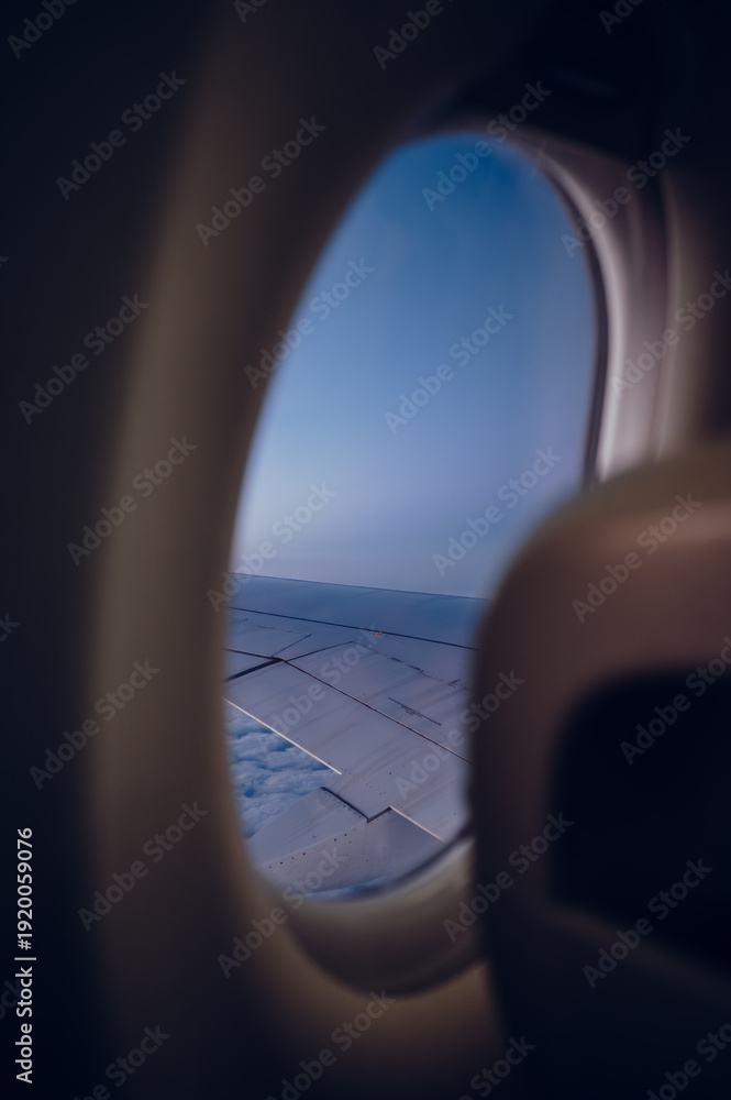 Fototapeta premium Airplane View with Wing Above the Clouds – Window Seat Perspective