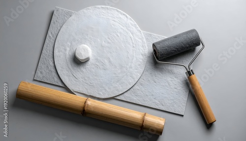 Artistic tools round paper, roller, bamboo handle, on textured grey surface