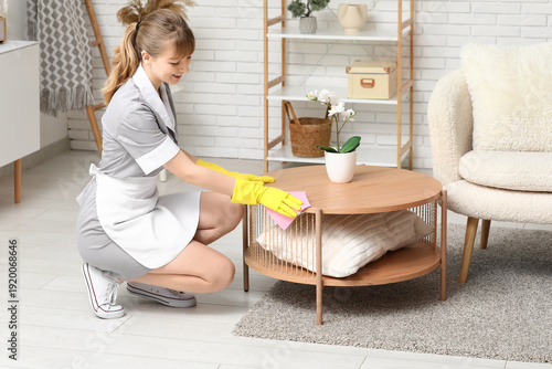 Maid with rag cleaning wood...