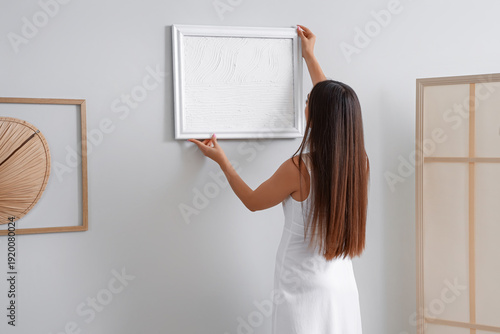 Young woman hanging paintin...