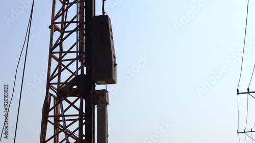 Heavy duty hydraulic pile driver machine hammering a concrete pillar at a construction site for deep foundation work.