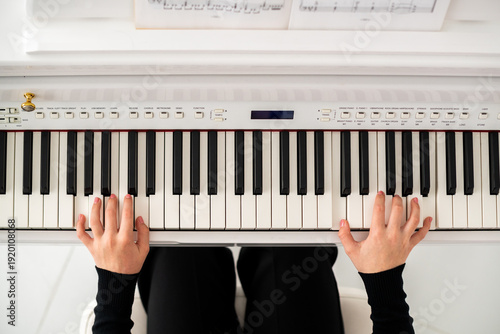 teenager's hands are playing on a digital piano, top view.