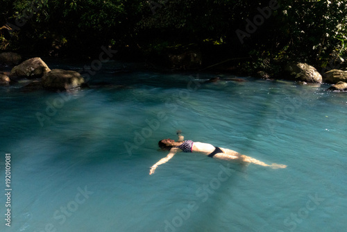 A woman floats on her back in turquoise water.