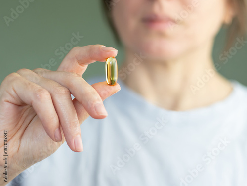 Quadro em tela Close-up of woman's hand holding transparent capsule with Omega-3