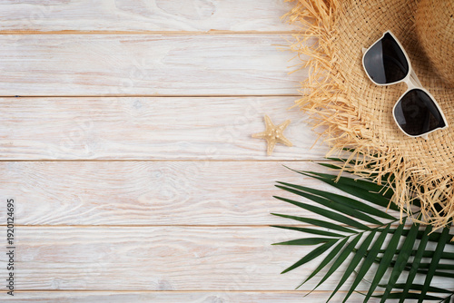 Vacation travel planning simple background of straw hat sunglasses palm leaves and starfish on white planks flat lay with copy-space