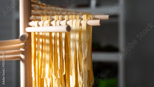Homemade noodles hanging on wooden dryer rack closeup low angle view