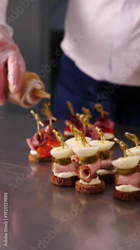 Pouring olive oil onto delicious bruschetta topped with fresh tomatoes, sliced beef with restaurant background. Vertical footage. Catering. Healthy eating. Italian cuisine. Cooking food. 4 k video