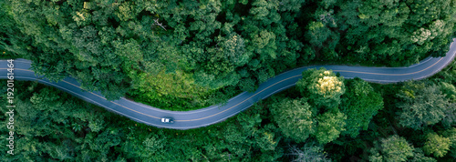 Aerial forest road with car creating abstract background for electric vehicle, ESG, sustainability and green investment business concepts.
