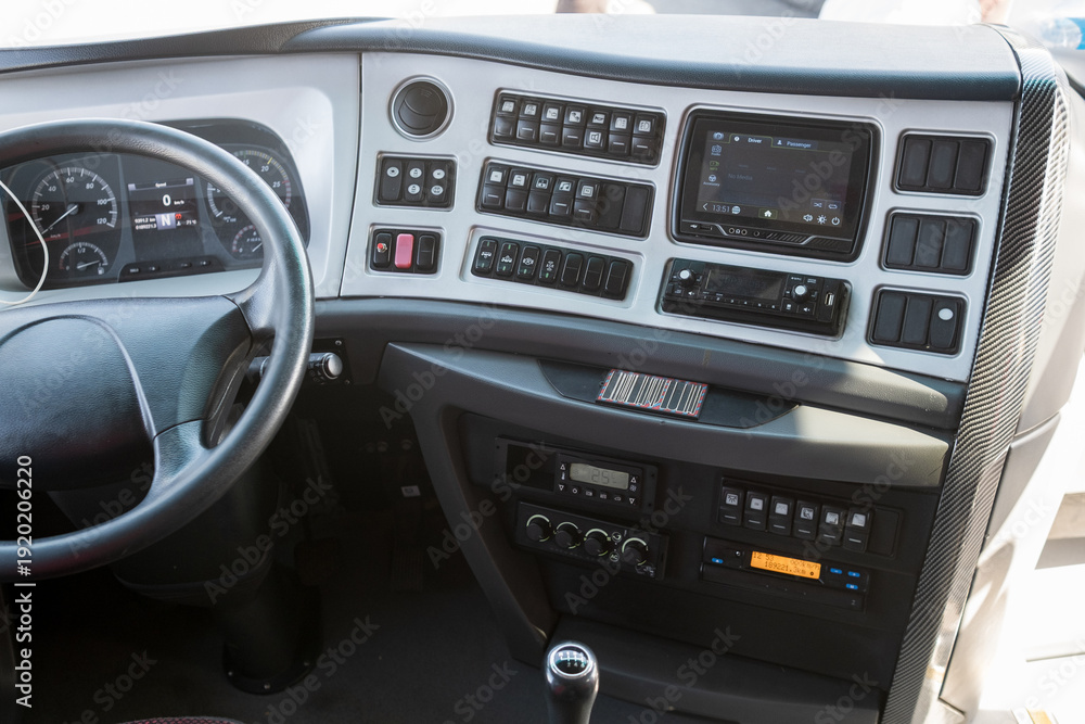 Obraz premium Interior view of a modern truck cabin featuring dashboard controls, steering wheel, and digital display for navigation and entertainment systems