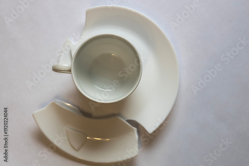 Broken cup and saucer sit on a flat surface with a simple design and color in a kitchen or dining space