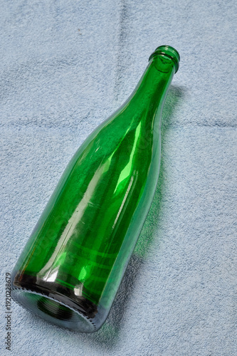 large, empty green bottle resting on a blue cloth