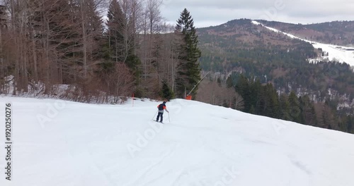 Drone follow shot of skier carving down snowy alpine slope