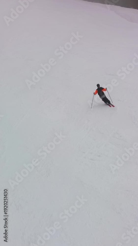 Drone follow shot of skier carving down snowy alpine slope