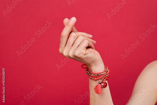 Fotografi Hand making crossed fingers gesture against solid red background, adorned with r
