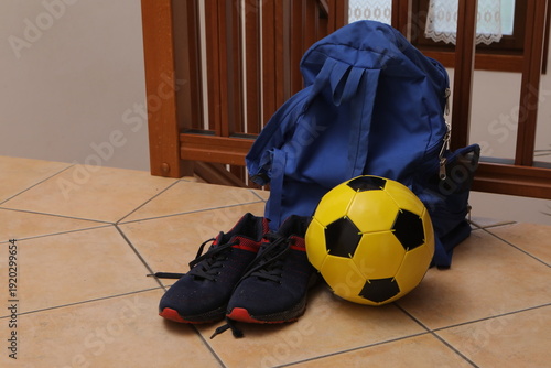 Backpack, soccer ball, sneakers on home floor