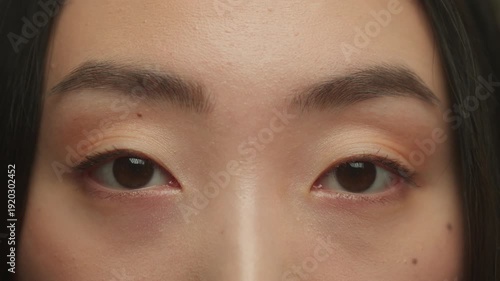 Close up Asian ethnic woman female black eyes looking at camera blinking natural beautiful face Korean Japanese Chinese girl eyesight vision laser correction medicine blink long eyelashes health care