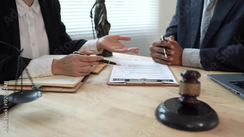 Two lawyers discuss legal documents at a desk, with a scale of justice and gavel symbolizing law, authority, and professional legal consultation in a modern office.