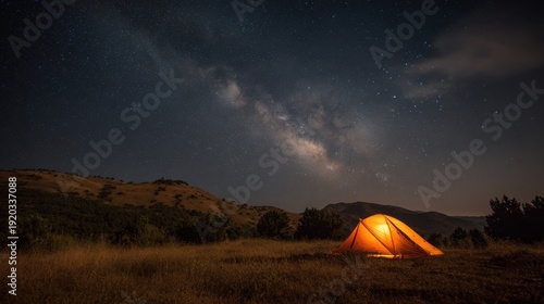 orange tent glowing beneath milky way sky, secluded bivouac in gentle valley with rolling slopes, warm lamp inside contrasts cool stellar band, peaceful night for rest and reflection