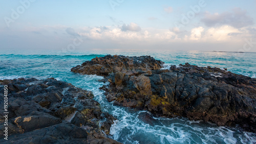 Fotografie Rocky coastline with turquoise waves under pastel sky