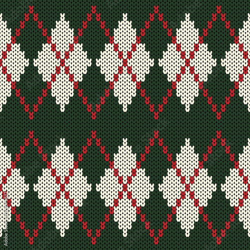 A knitted sweater in a diamond pattern, in dark green tones contrasting with cream white.