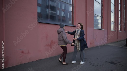 Woman walks with coffee near a building with large windows in the city during daytime