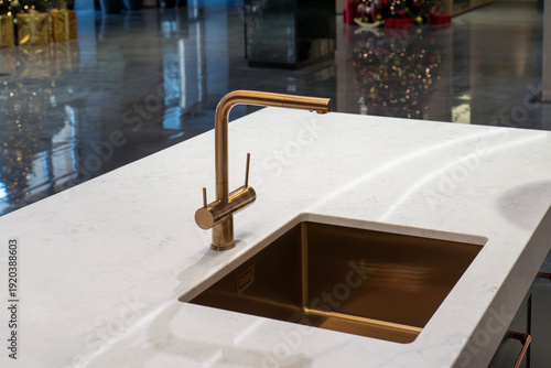 Gold kitchen faucet and undermount sink on white marble countertop