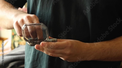 Close-up of a man holding a plastic pill organizer and taking medication. Concept of healthcare, daily supplement routine, and medical treatment
