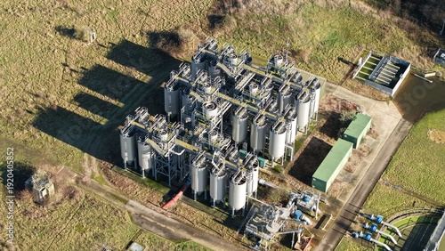 Aerial view of a sprawling complex of silver tanks and industrial architecture dominates the landscape, contrasting with the surrounding fields, Luton, United Kingdom.