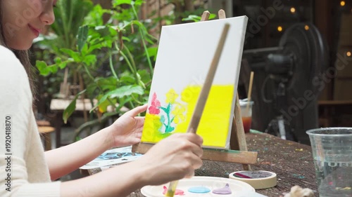 Happy young adult asian woman painting brush on canvas at workshop art lesson class outdoor cafe creativity hobby